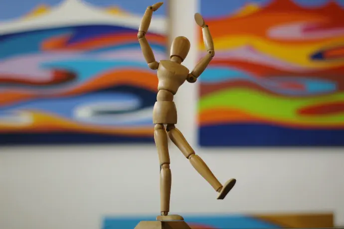a wooden figure is posed in front of a painting